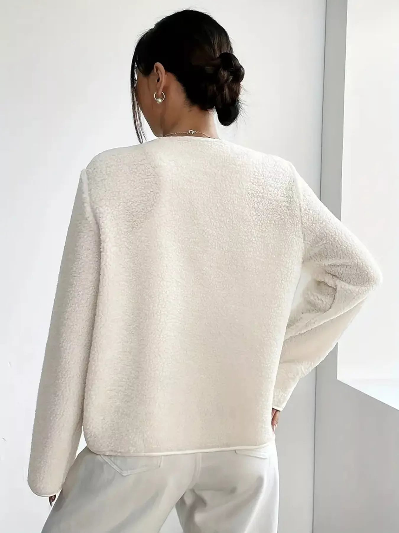 Person wearing a light-colored sweater against a white background