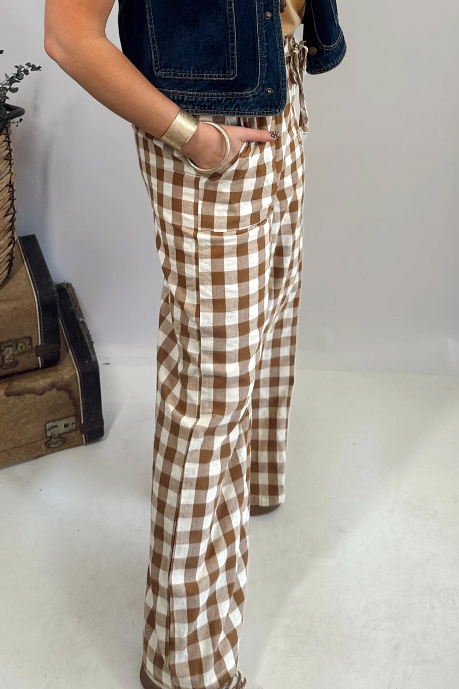 Person wearing brown and white checkered pants with a plain background side view