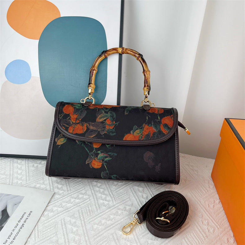 Floral-patterned handbag with a detachable strap on a textured surface.