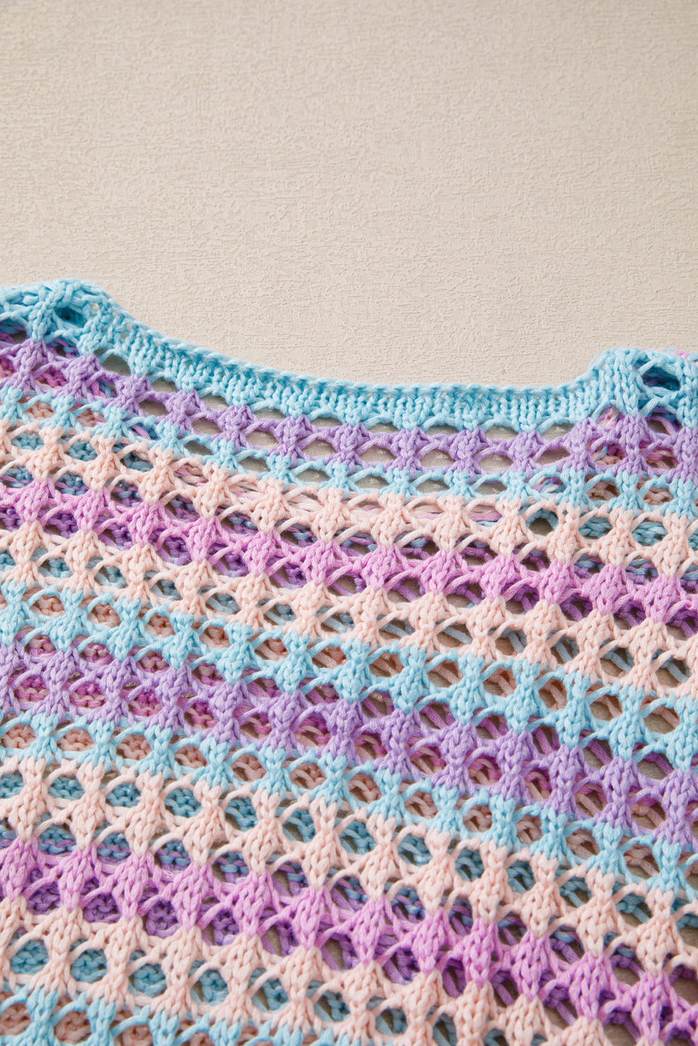Colorful crocheted shawl with a geometric pattern on a beige background