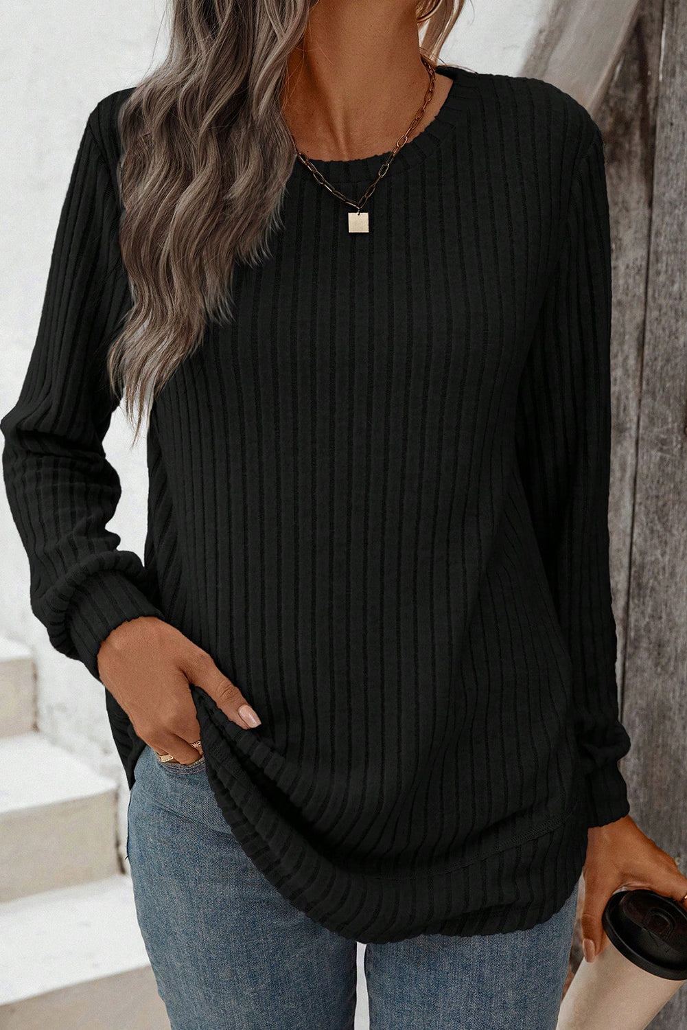 Person wearing a black ribbed sweater and blue jeans indoors.