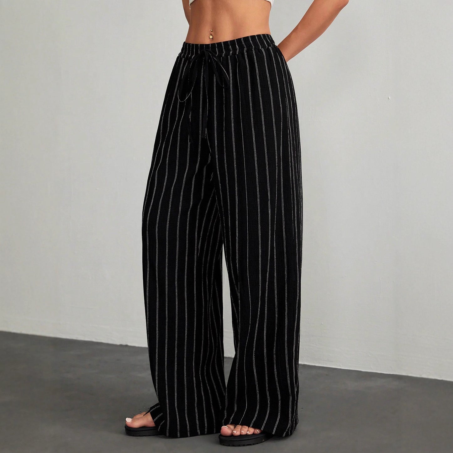Black pinstripe pants worn by a person on a gray background