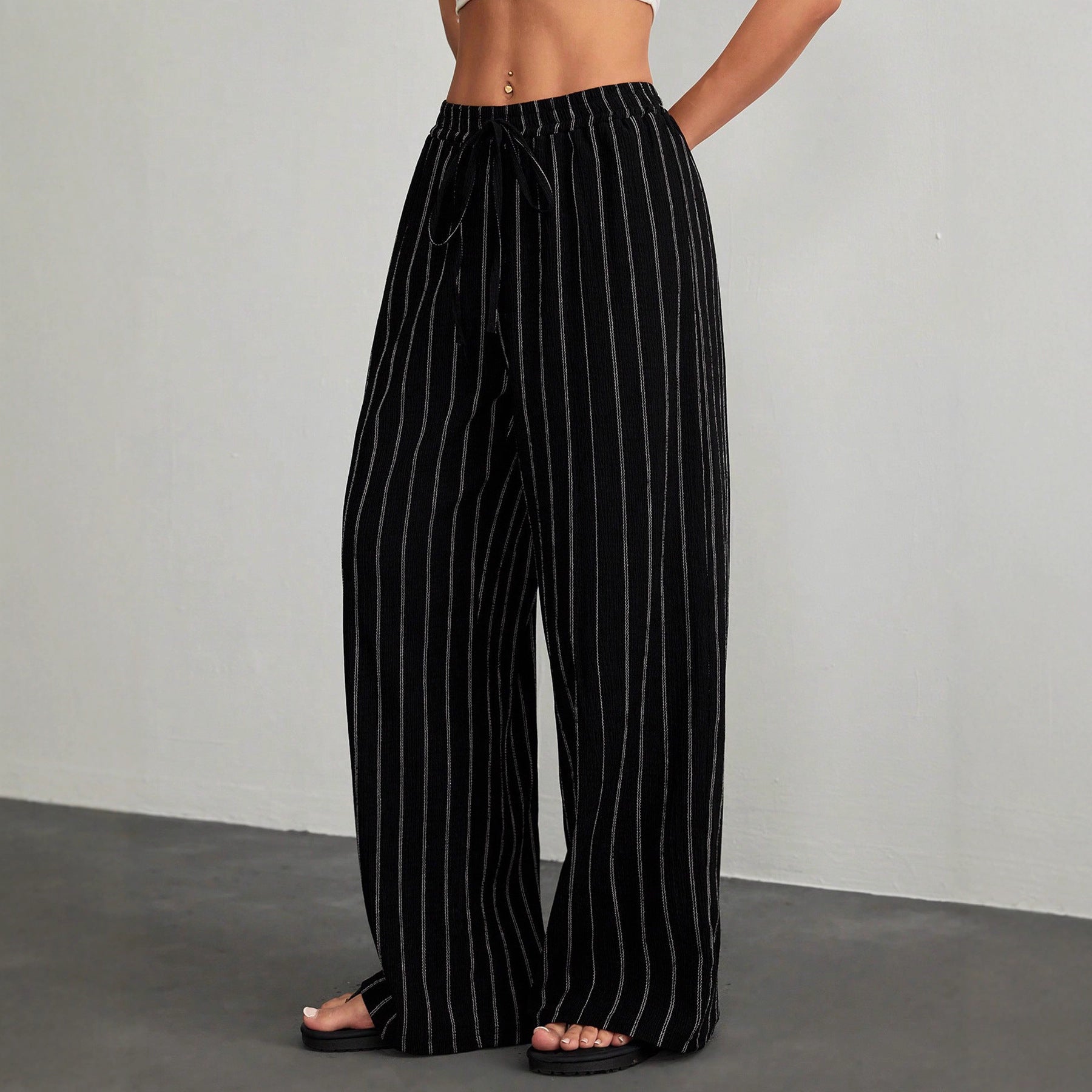 Black pinstripe pants worn by a person on a gray background