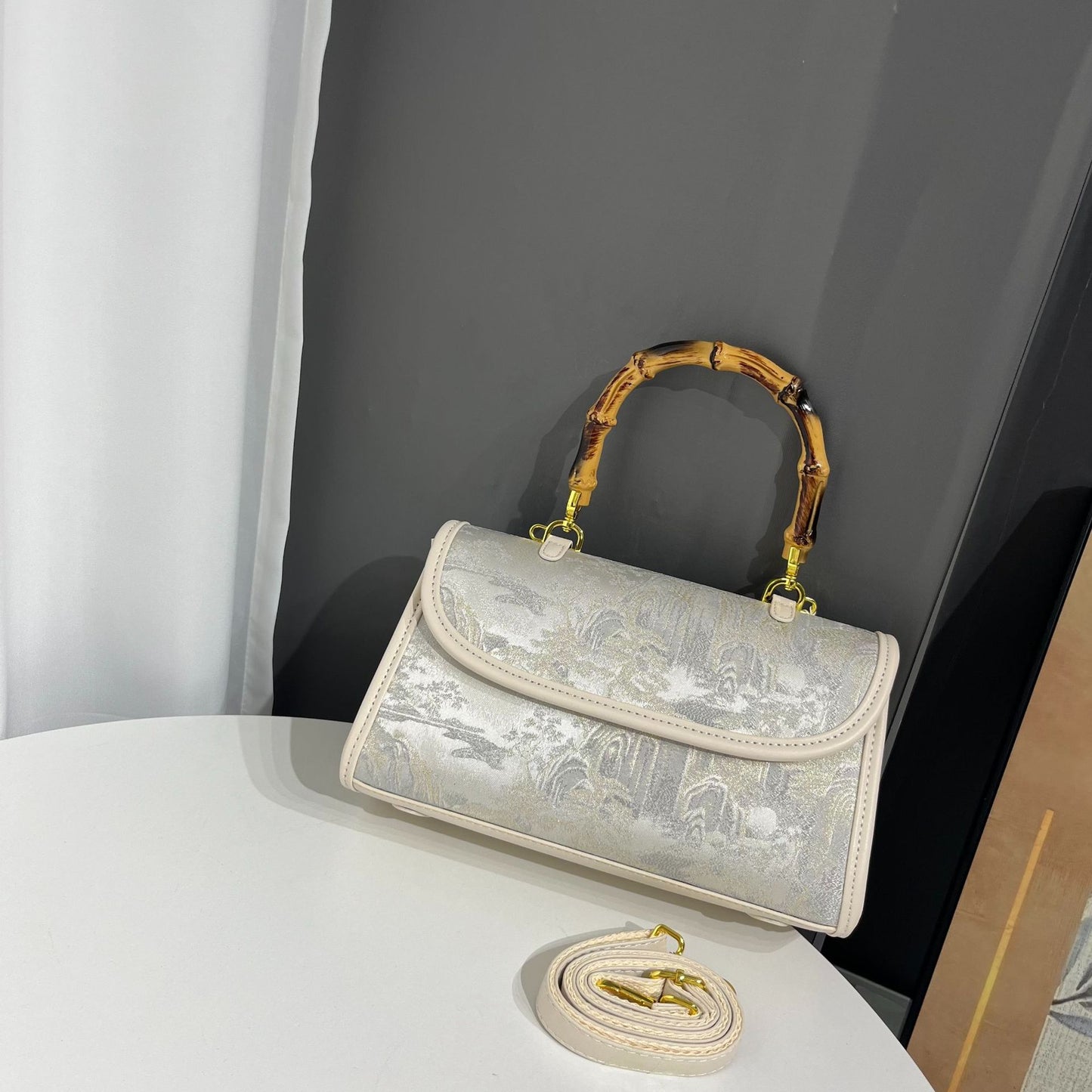 Silver handbag with bamboo handle on a white surface