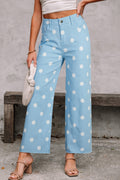 Person wearing light blue pants with white polka dots, standing against a concrete wall. Front view