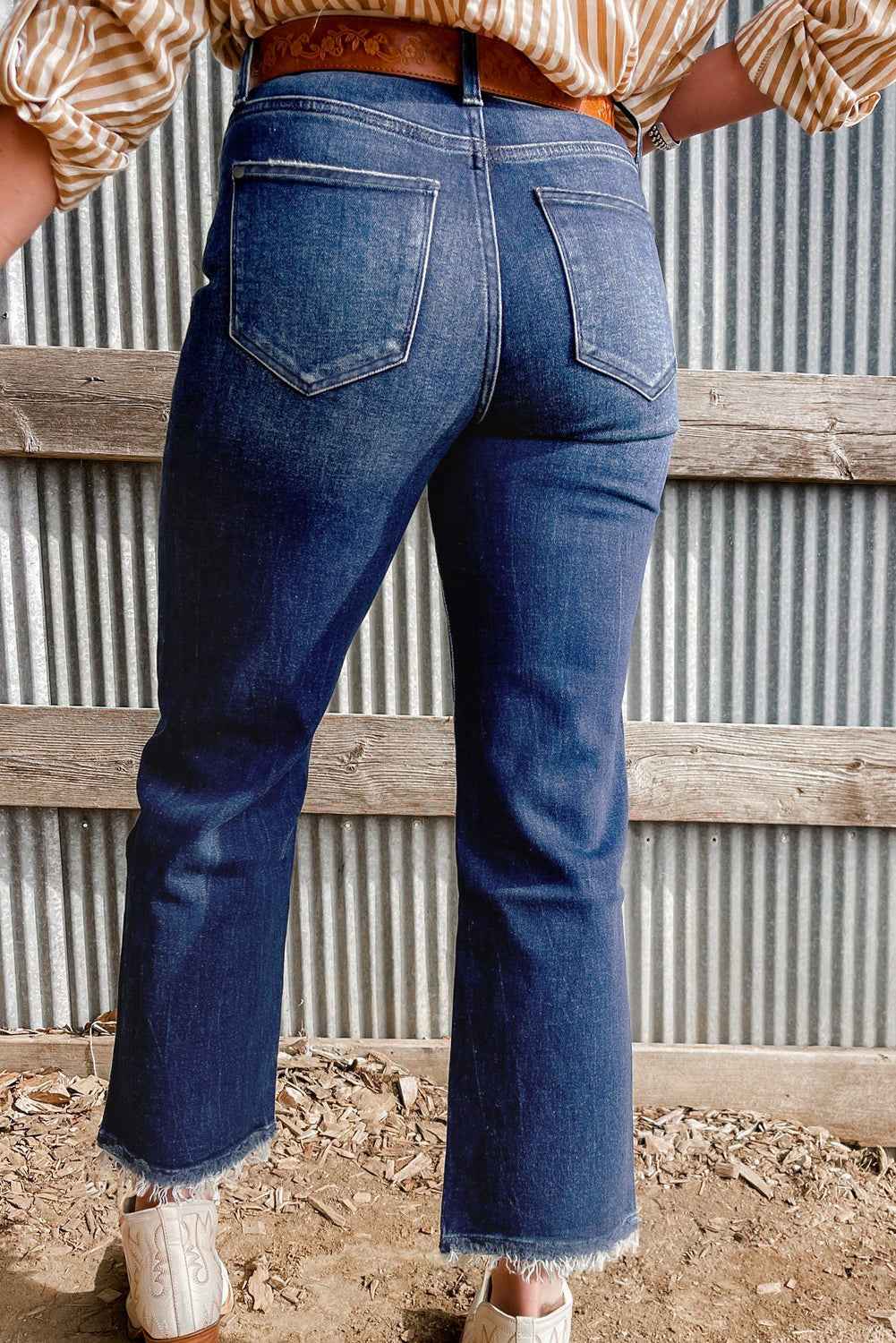 Person wearing blue jeans standing in front of a corrugated metal wall.