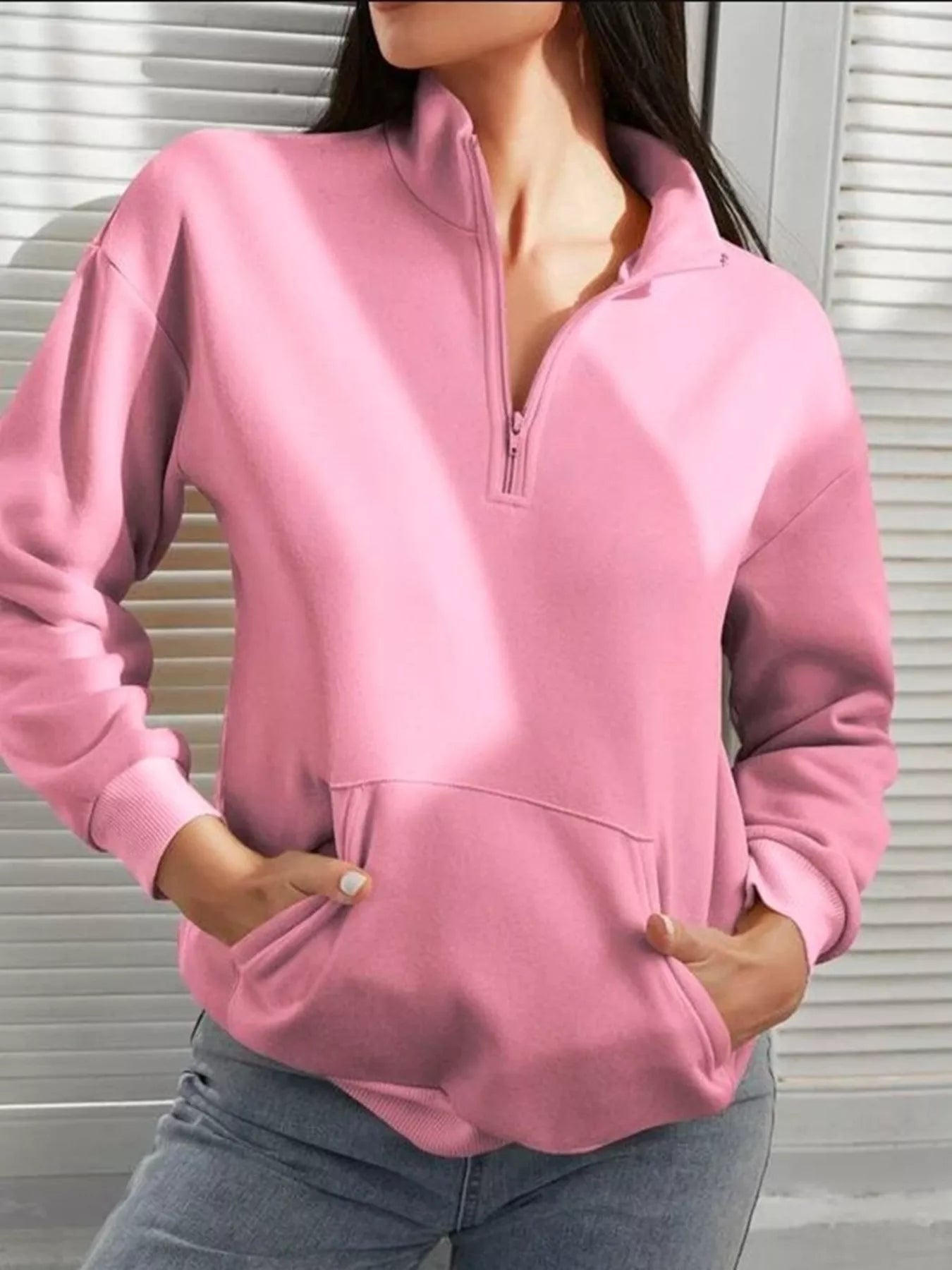 Person wearing a pink pullover with a zipper against a neutral background