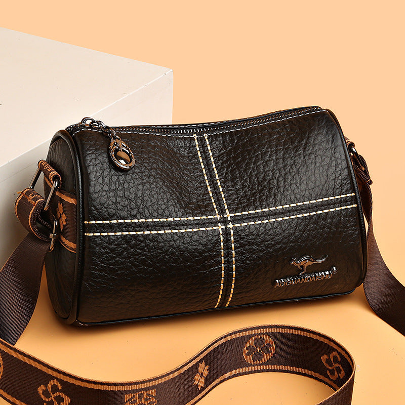 Black leather handbag with white stitching on a beige background