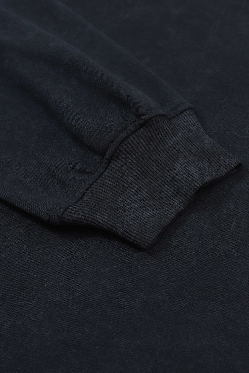 Close-up of a dark gray sweatshirt sleeve on a matching fabric background