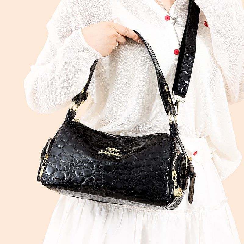 Black textured handbag held by a person wearing a white outfit on a beige background