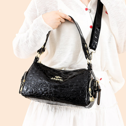 Black textured handbag held by a person wearing a white outfit on a beige background