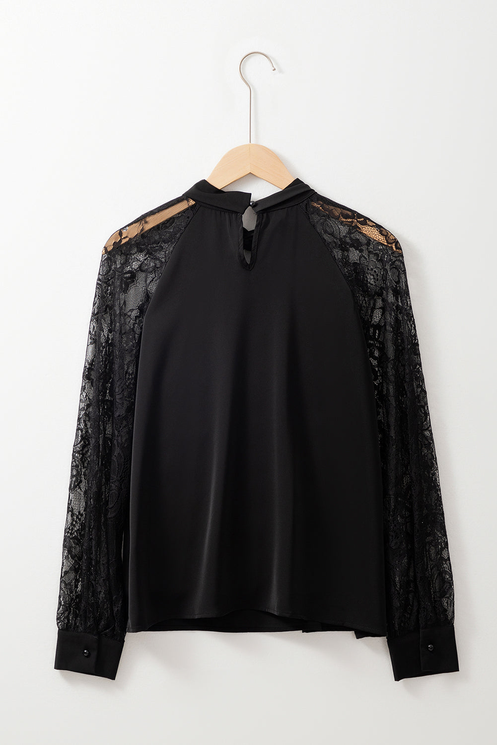 Black blouse with lace sleeves on a hanger against a white background