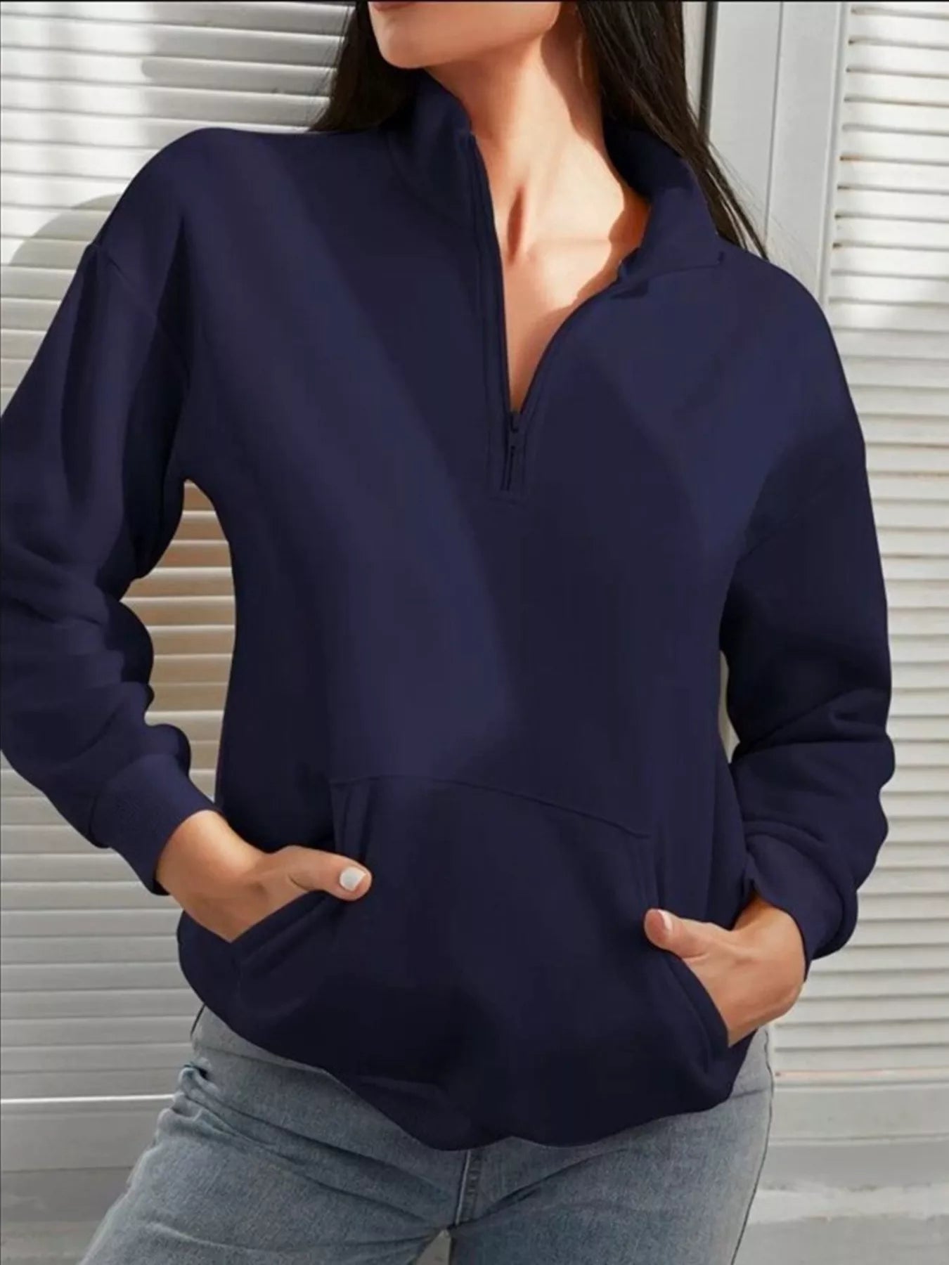 Person wearing a navy blue long-sleeve shirt with a neutral background