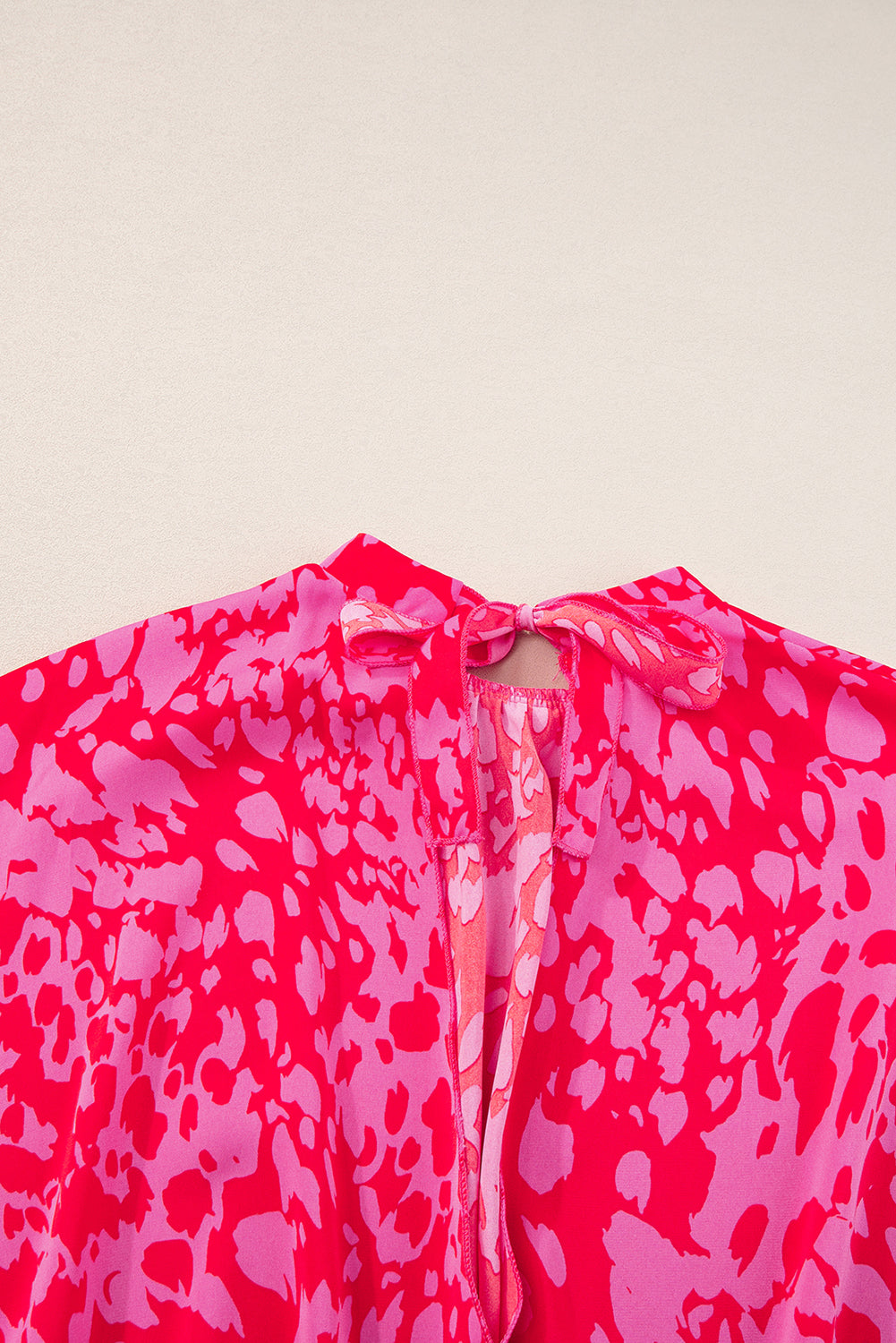 Pink and red patterned top on a beige background