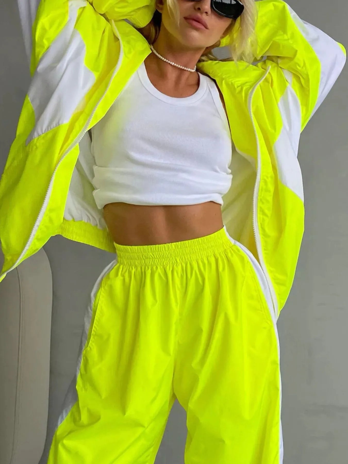 Person wearing a bright yellow tracksuit with white accents on a plain background