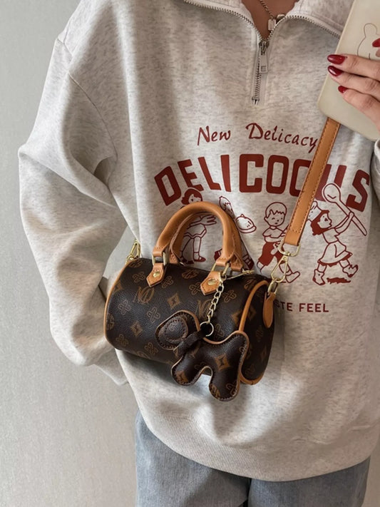 Person wearing a gray sweatshirt with a graphic design, holding a brown handbag.