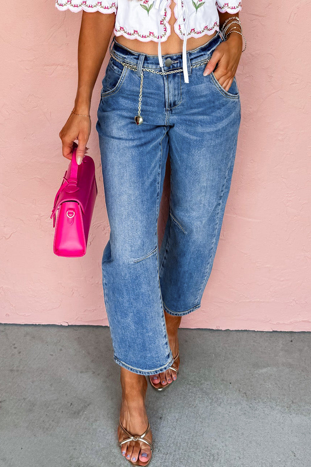 Person wearing blue jeans and a white top with pink background