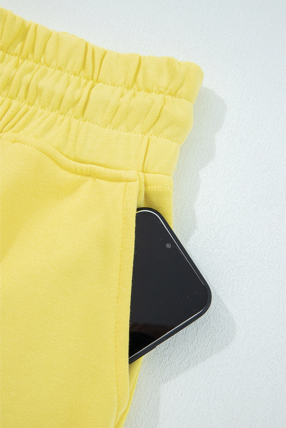 Yellow shorts with a smartphone on a white background