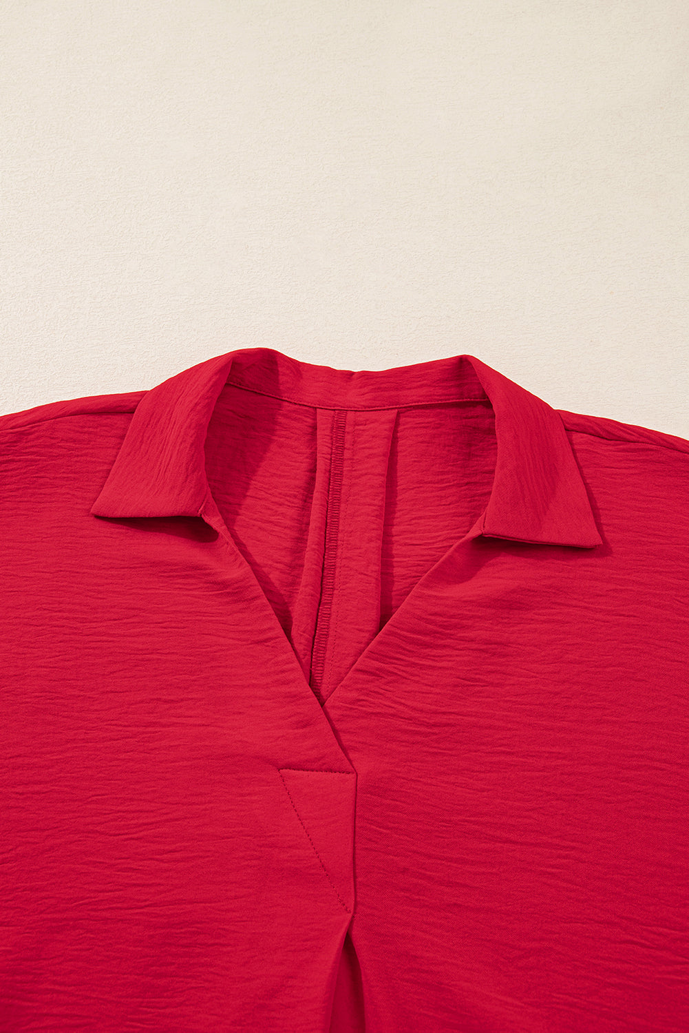 Close-up of a red shirt with a collar on a beige background
