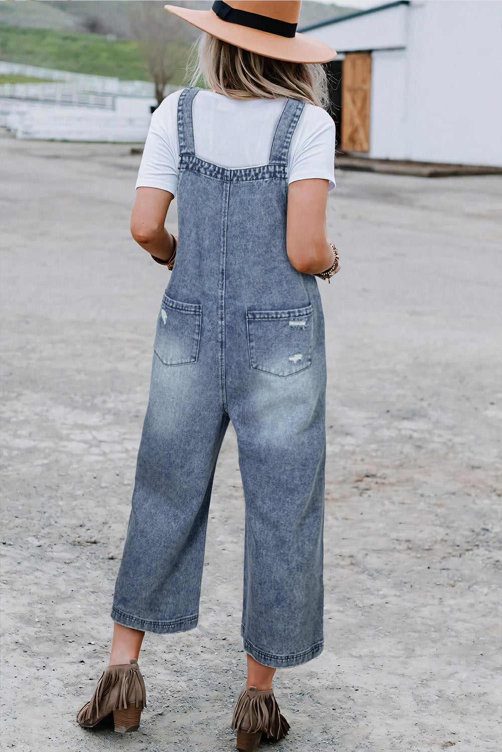 Person wearing denim overalls and a white shirt on a concrete surface.