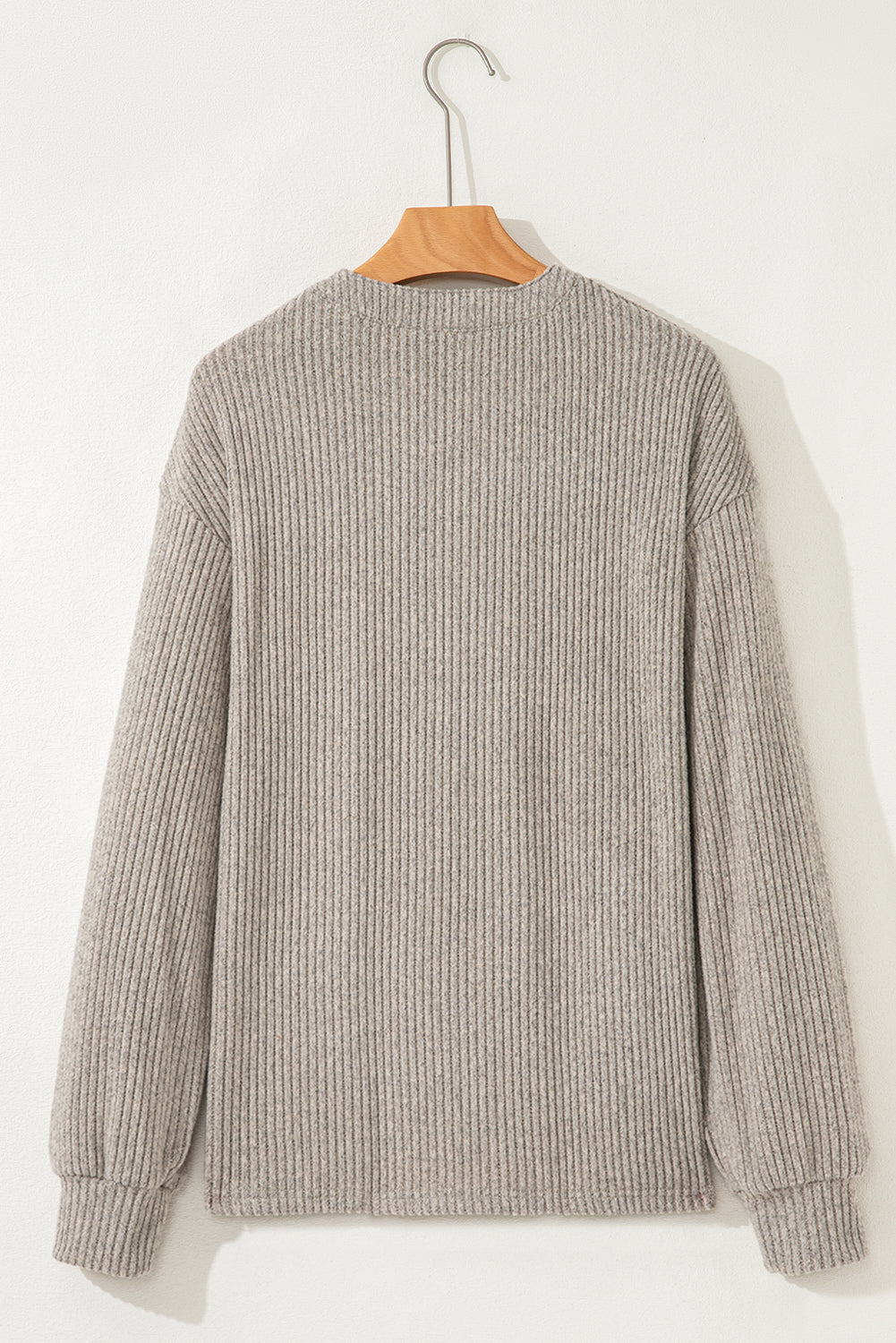 Gray ribbed sweater on a wooden hanger against a white background