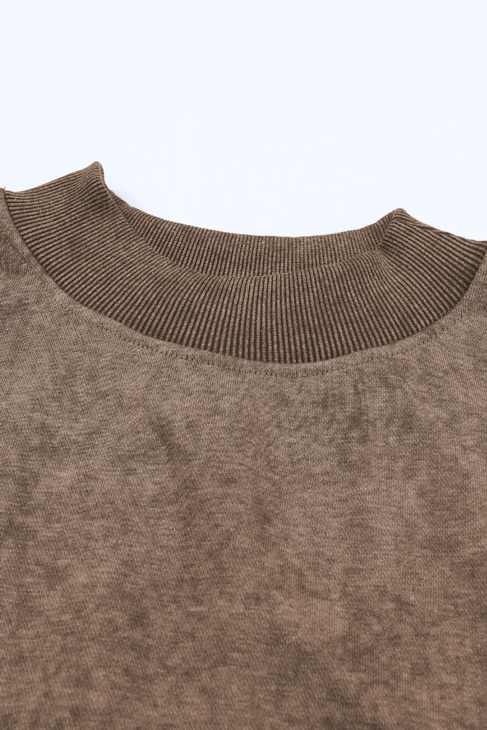 Close-up of a brown sweater collar on a light gray background