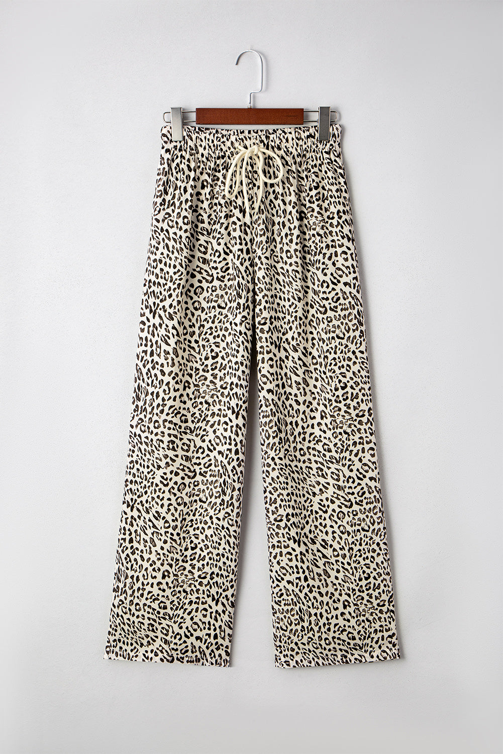 Leopard print pants on a hanger against a white background