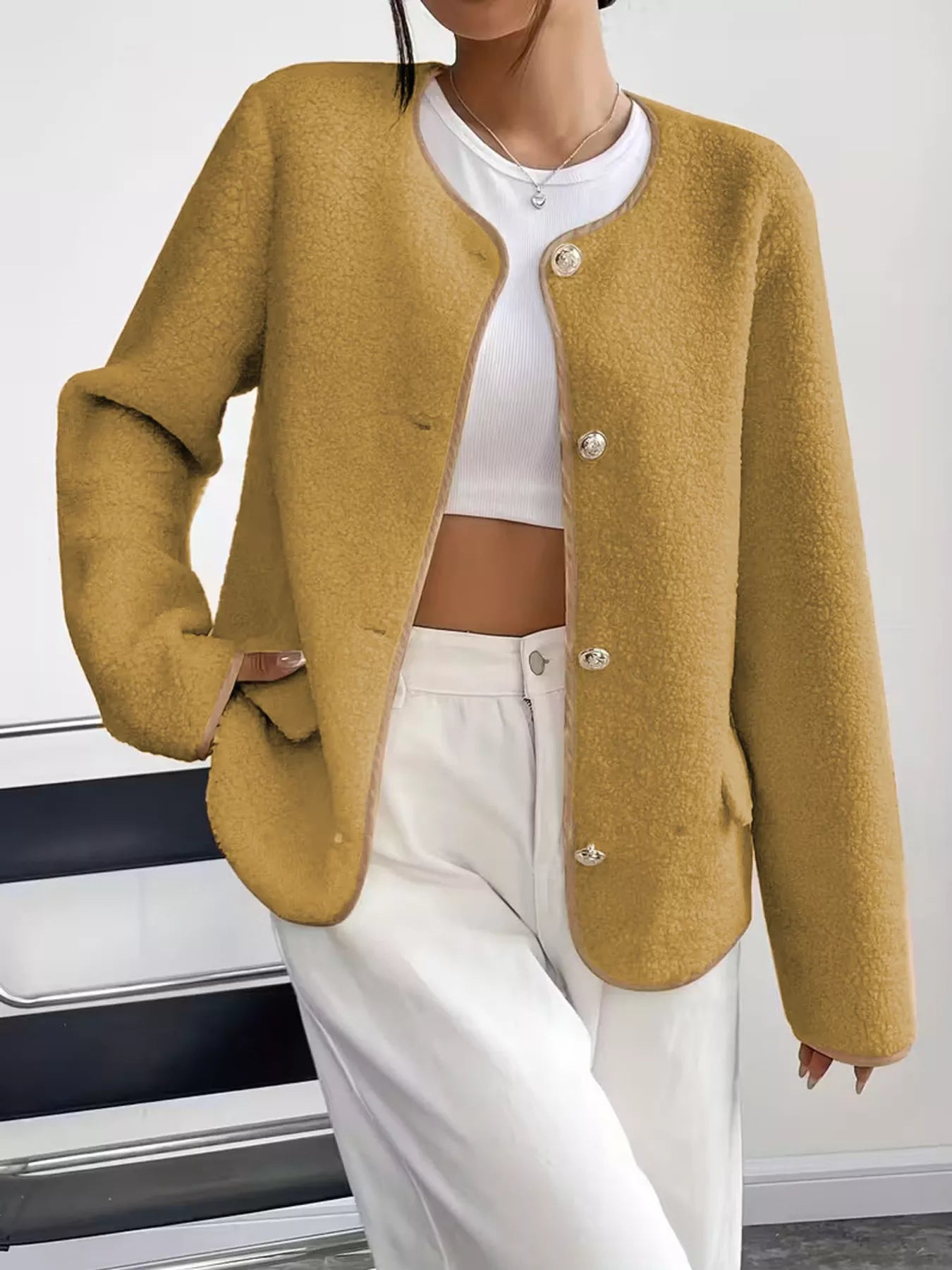Person wearing a mustard yellow cardigan over a white top and pants.