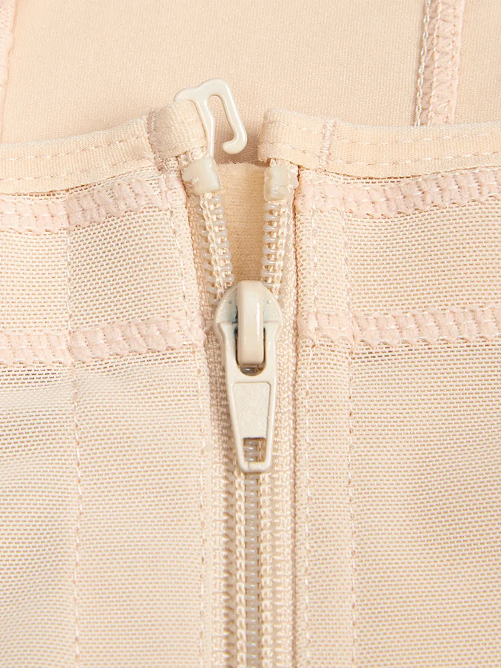 Close-up of a beige fabric with a zipper and white pull tab.