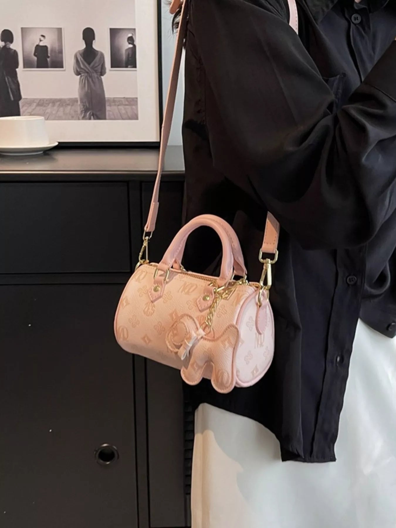 Person holding a pink handbag with gold accents in an indoor setting