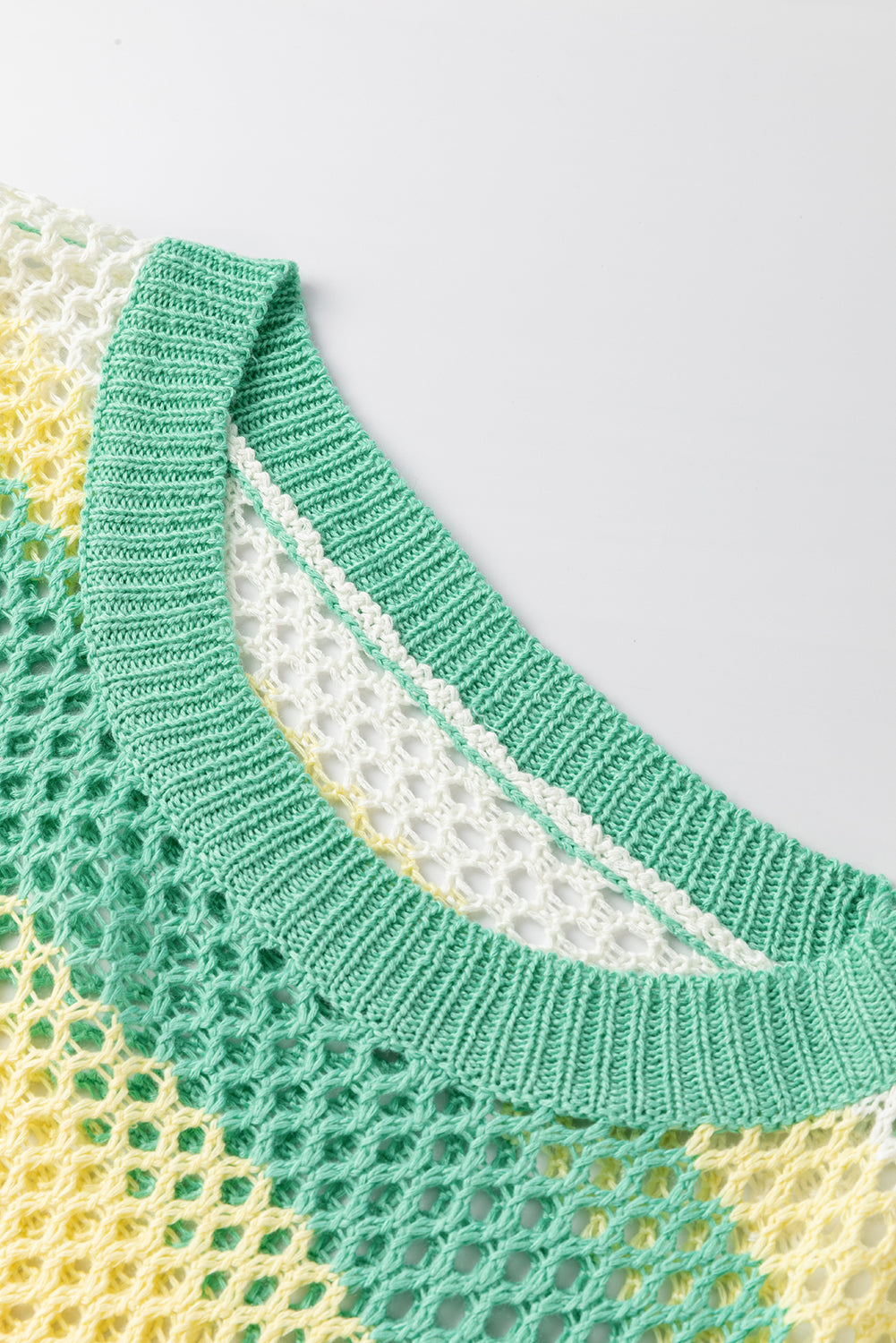 Close-up of a green and yellow knitted garment on a light gray background