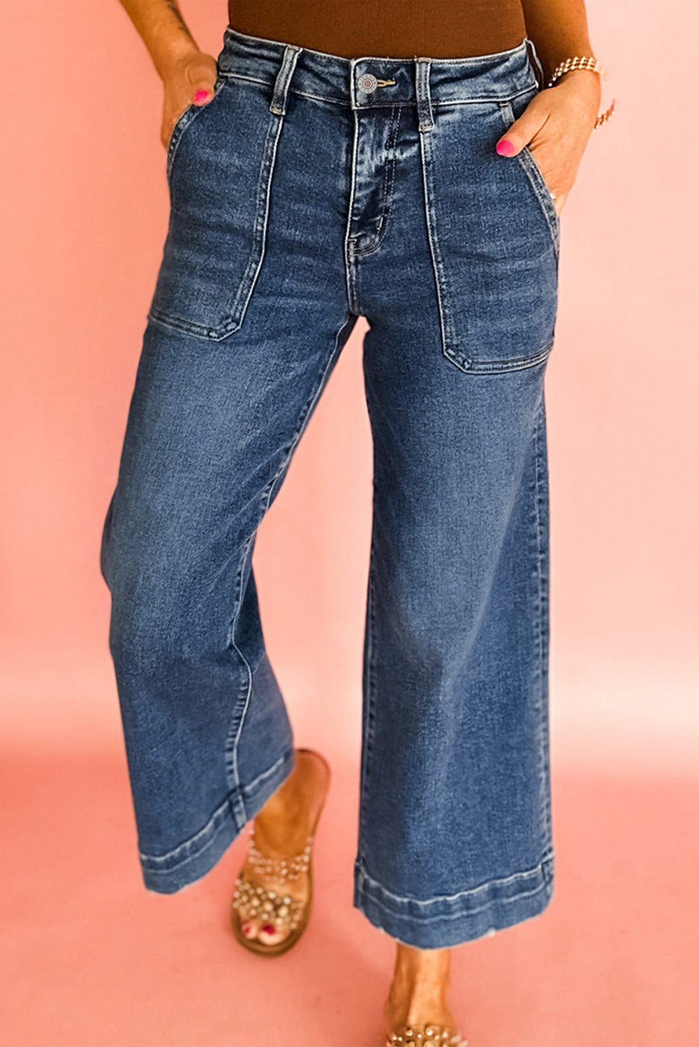Person wearing blue wide-leg jeans on a pink background