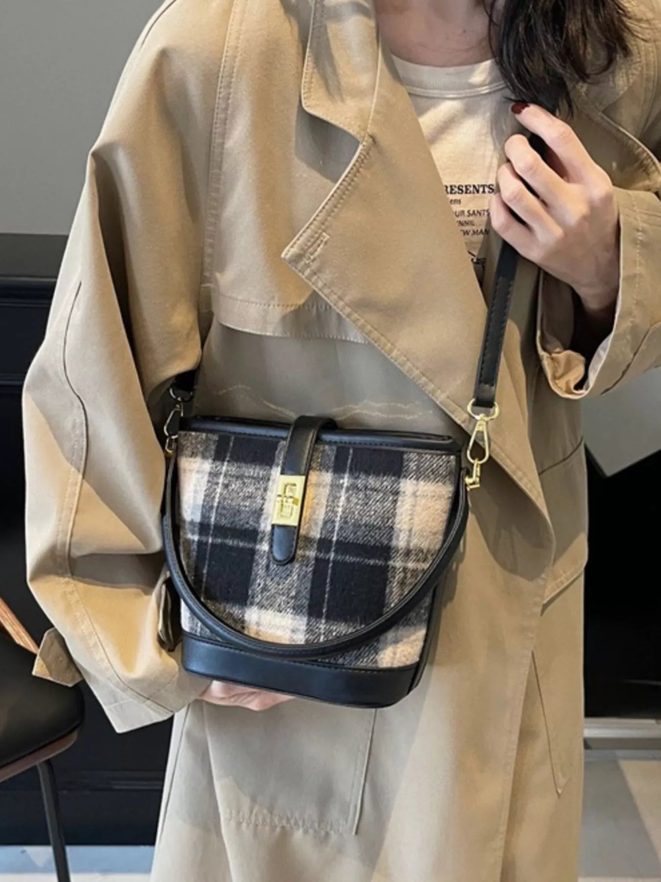 Person holding a plaid patterned bag with a neutral background