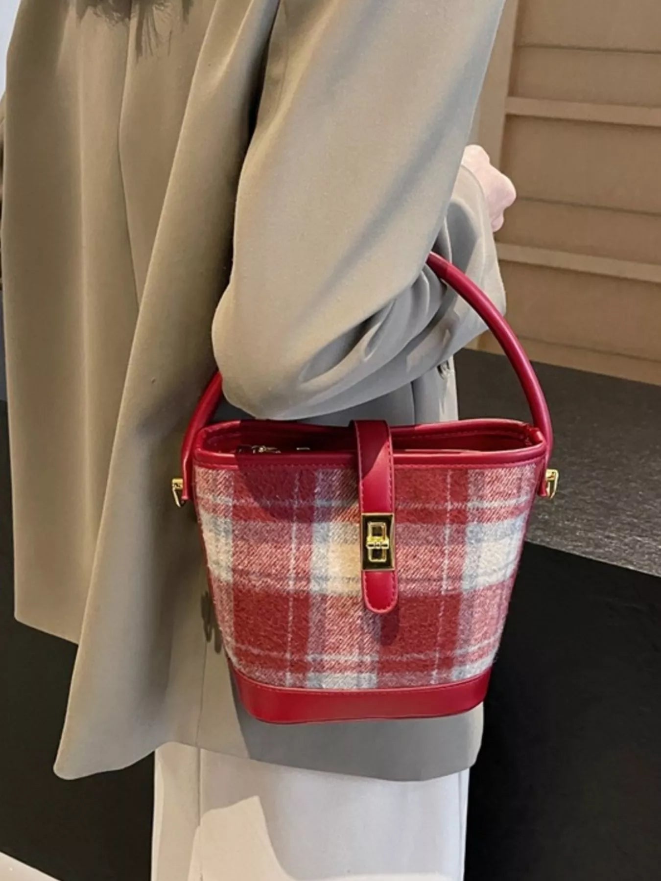 Person holding a red plaid handbag with a neutral background