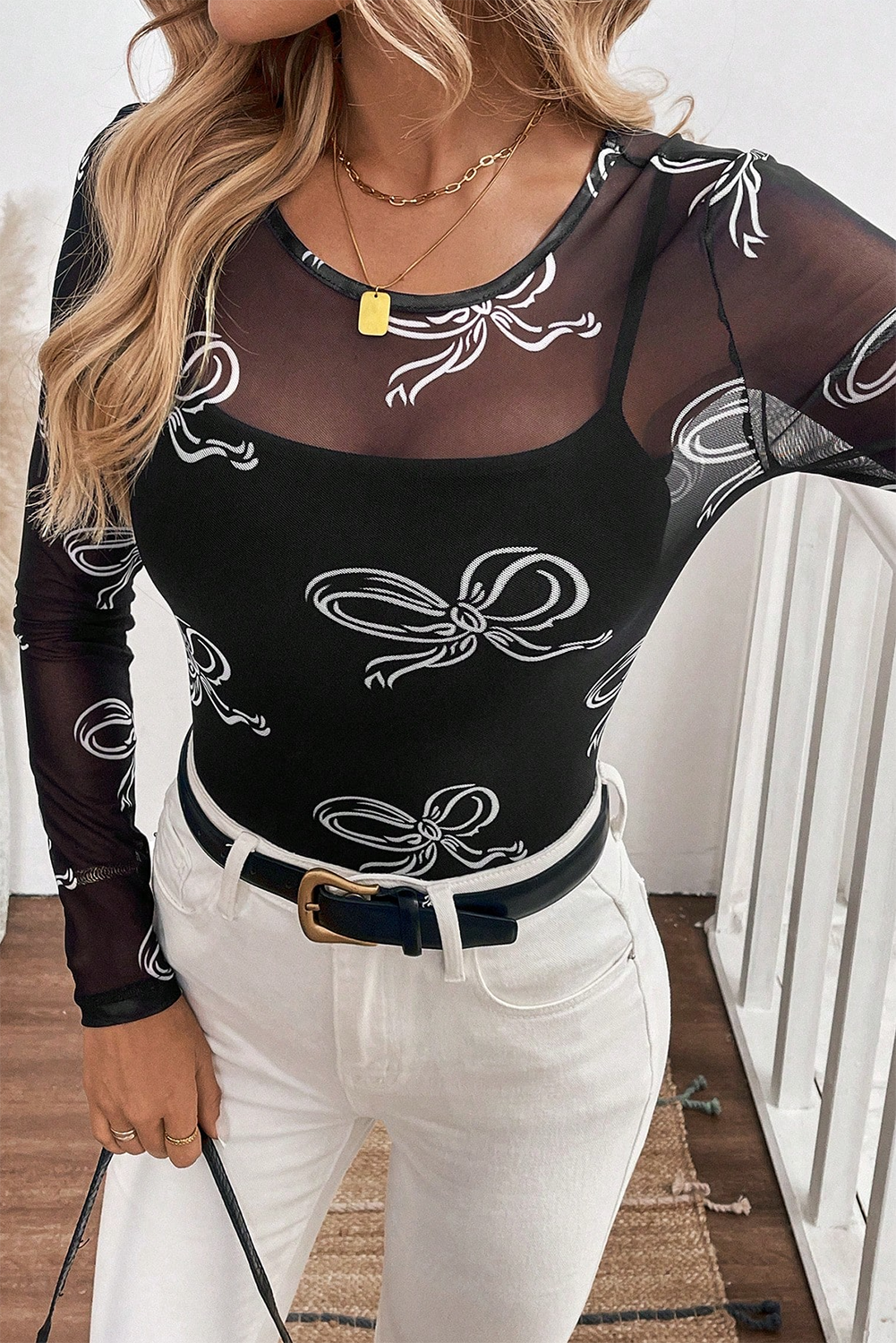 Person wearing a black long-sleeve top with white bow patterns and white pants.