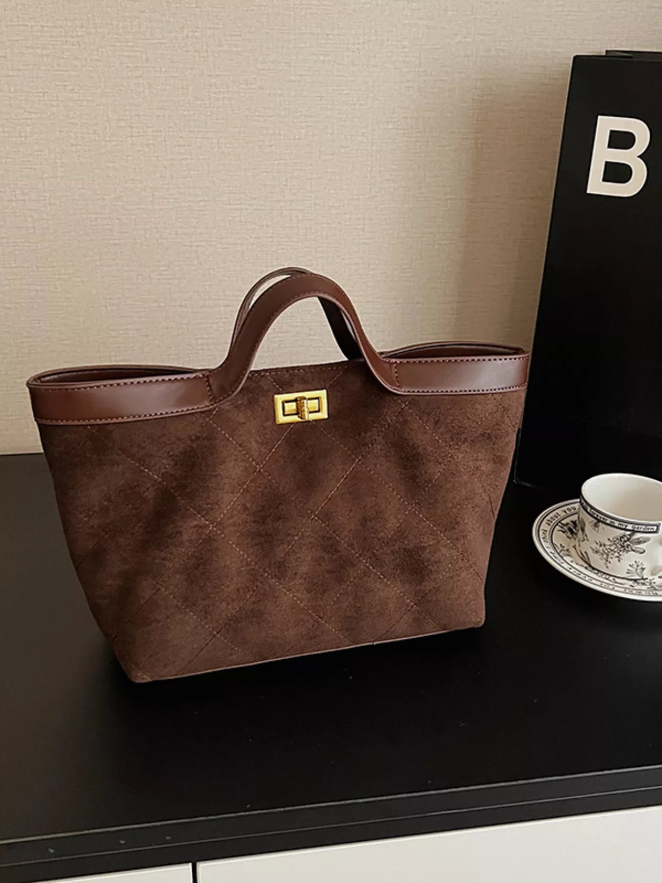Brown handbag on a dark surface with a textured wall background