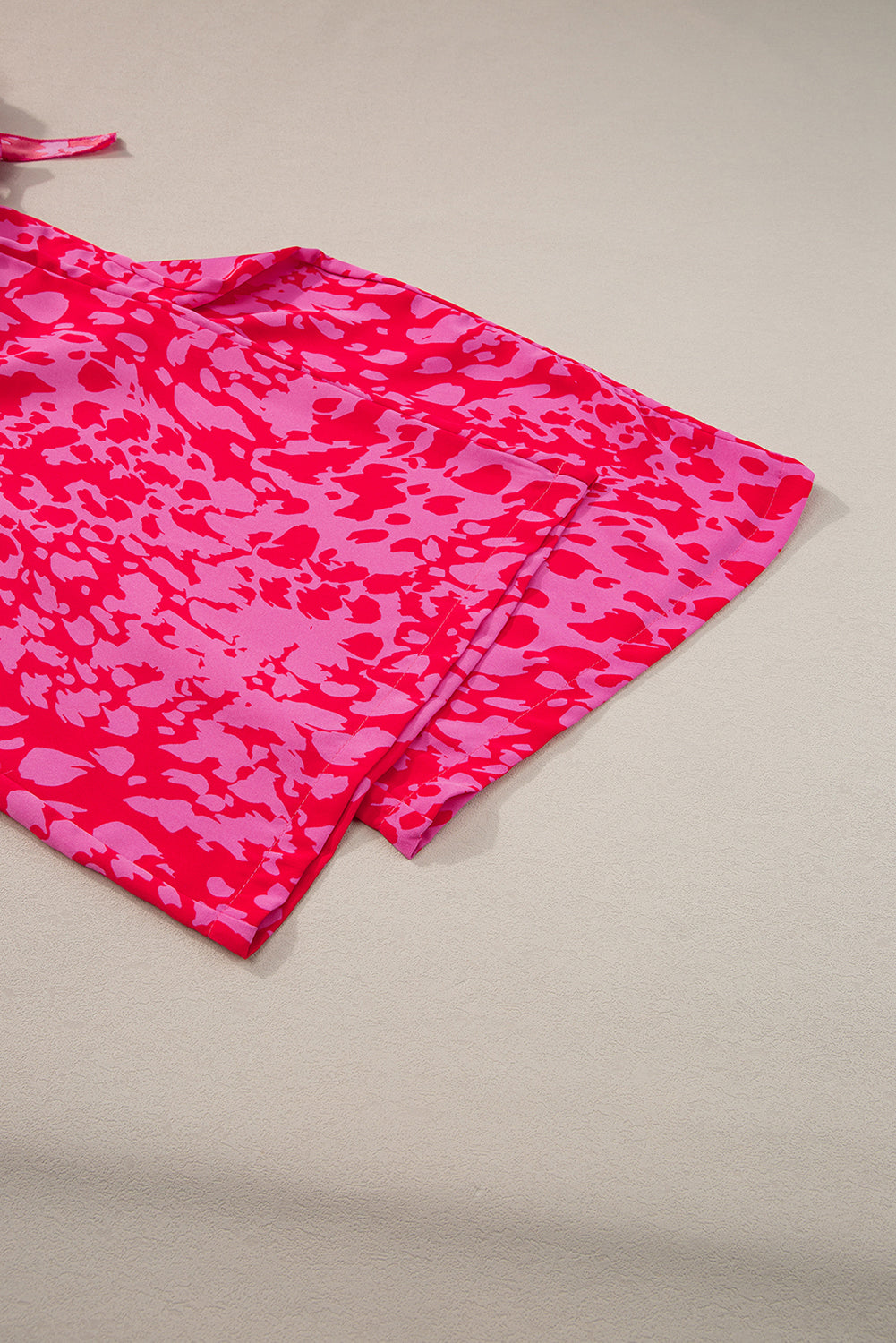 Pink camouflage-patterned fabric on a beige background