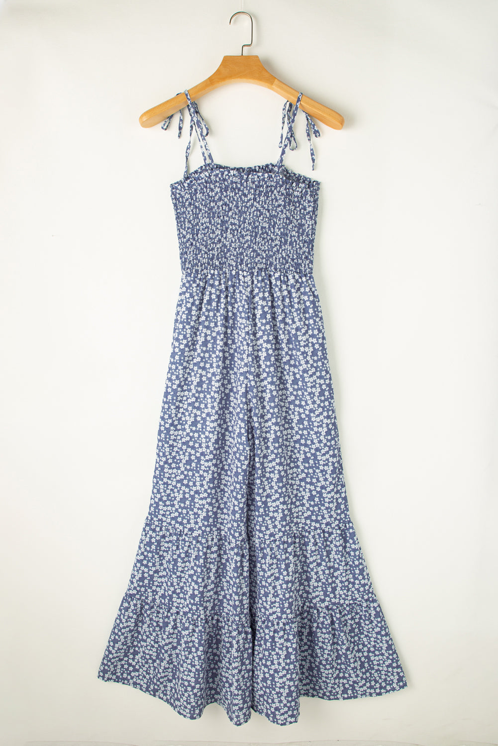 Blue floral dress on a hanger against a white background