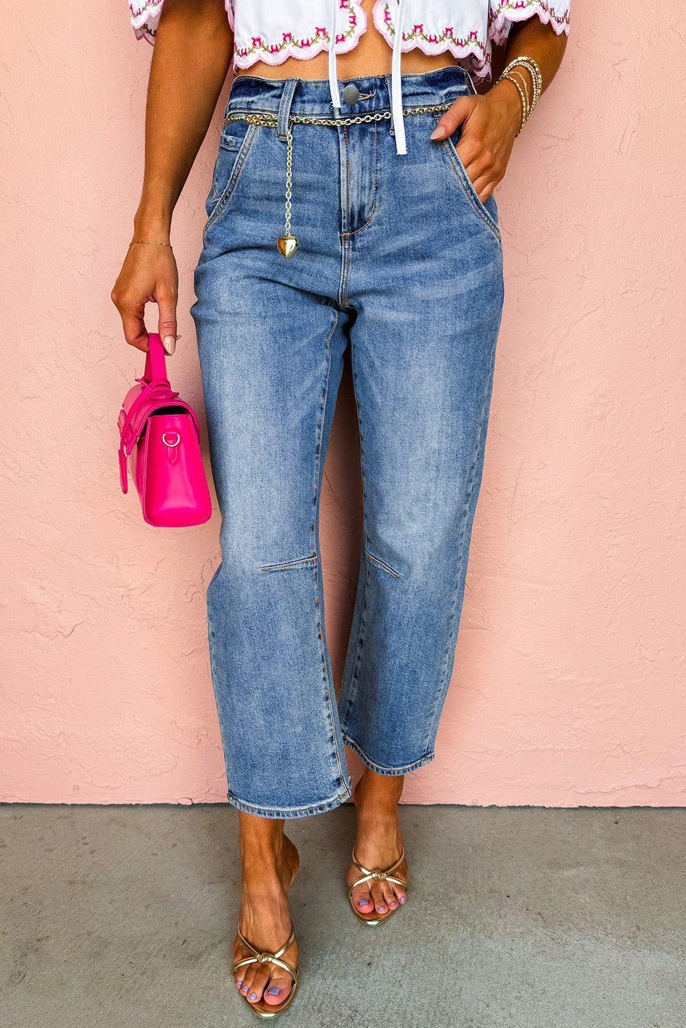 Person wearing blue jeans and a white top with a pink background