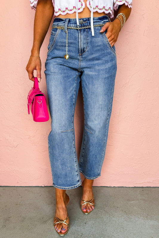 Person wearing blue jeans and a white top with a pink background