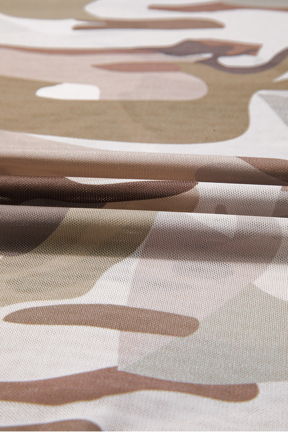 Close-up of camouflage-patterned fabric with brown, beige, and white colors.