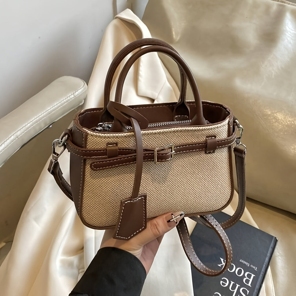 Beige handbag with brown accents held by a hand on a beige fabric background