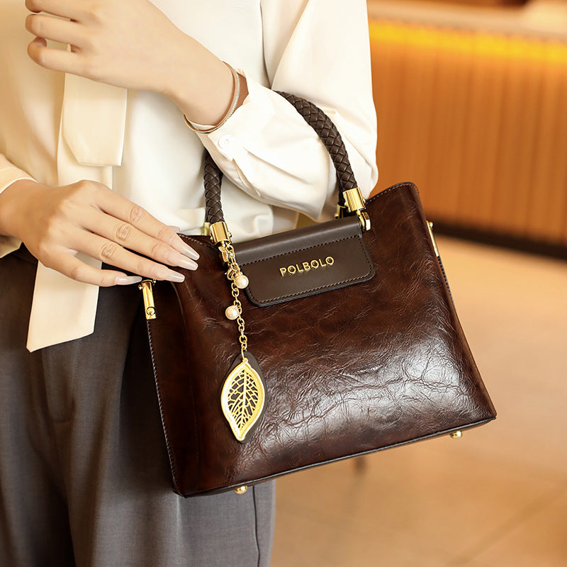 Brown handbag with gold accents held by a person, brand 'Polboho' visible