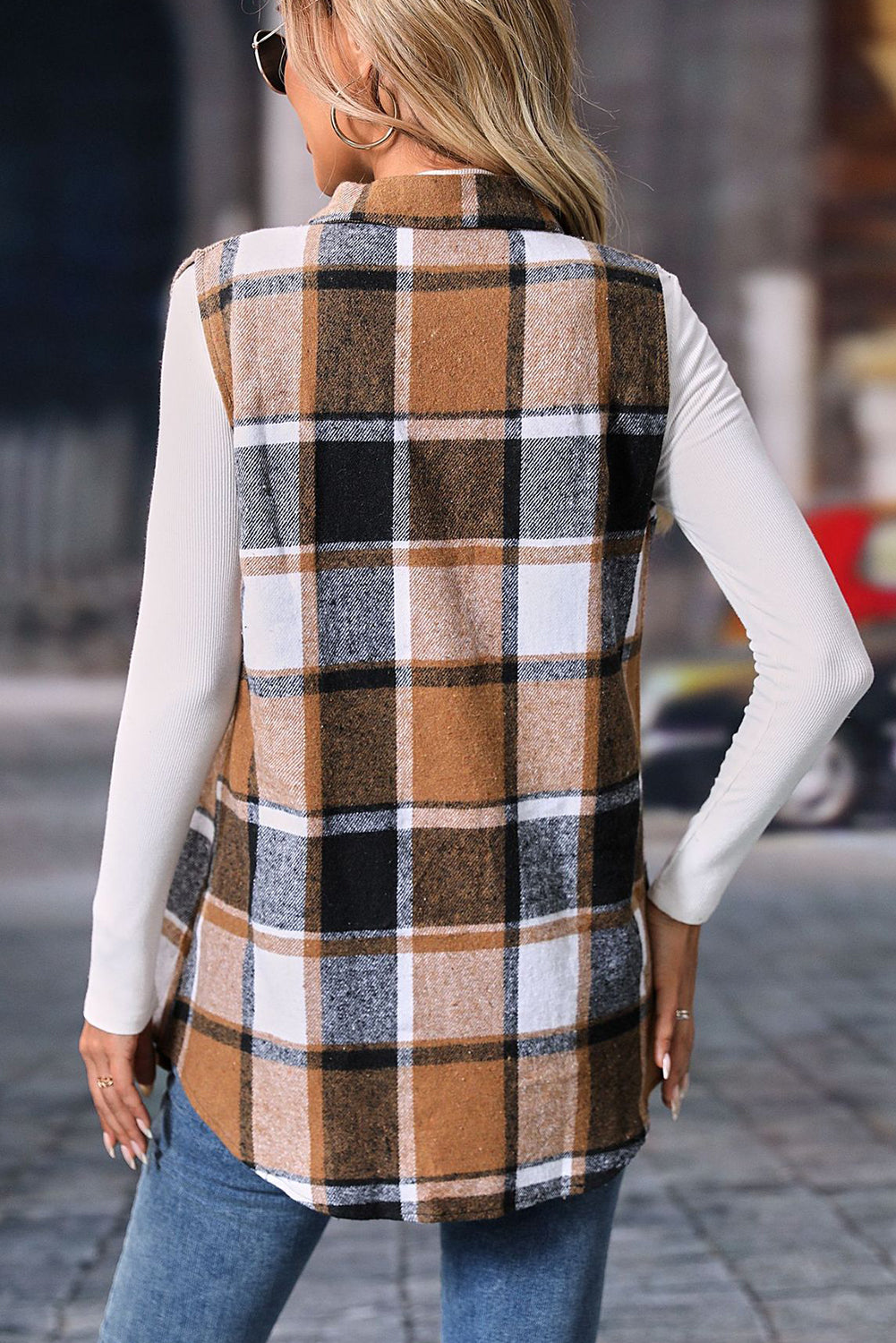 Person wearing a plaid vest on a city street