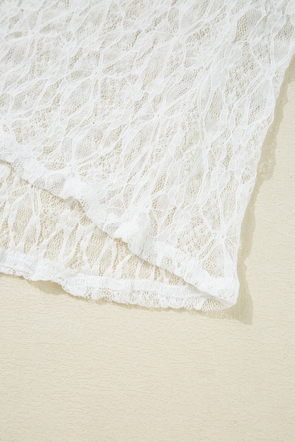 Close-up of white lace fabric on a beige background