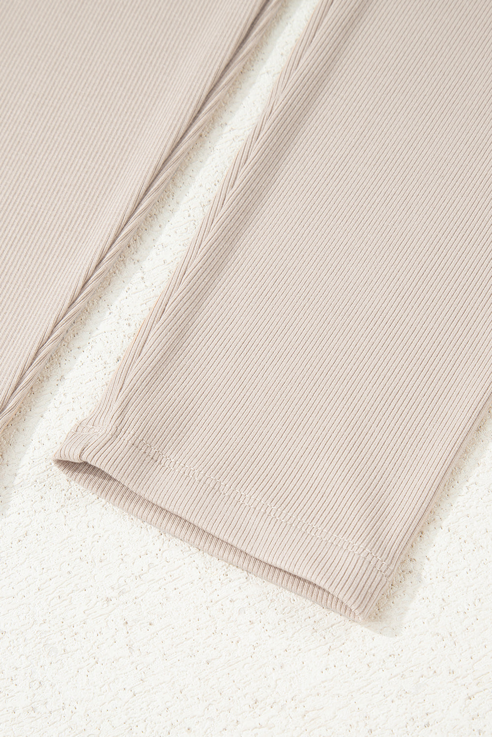 Close-up of beige ribbed fabric on a textured white background