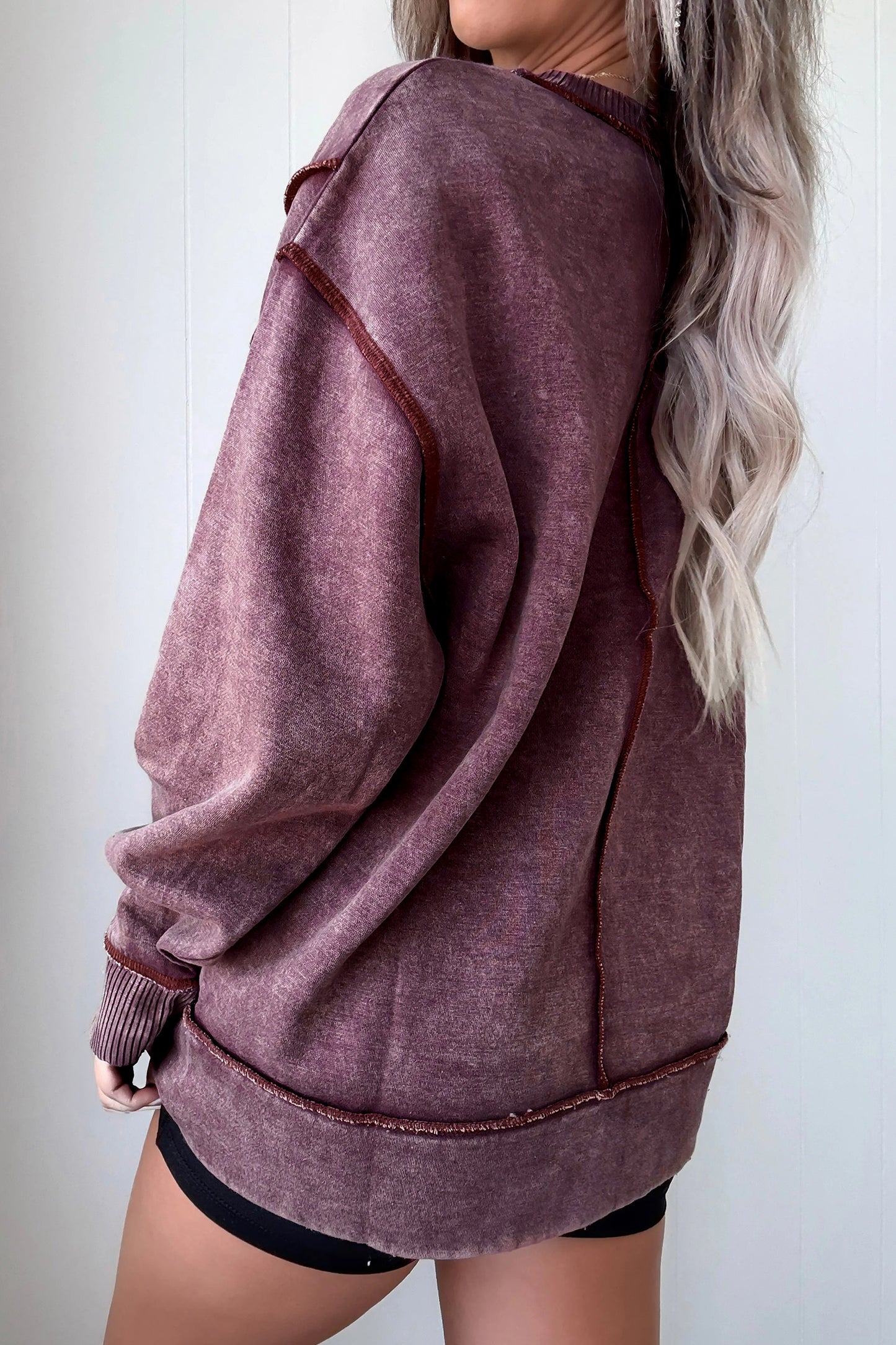 Person wearing a maroon oversized hoodie with a plain background