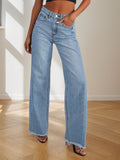 Person wearing light blue jeans standing on a wooden floor with a neutral background
