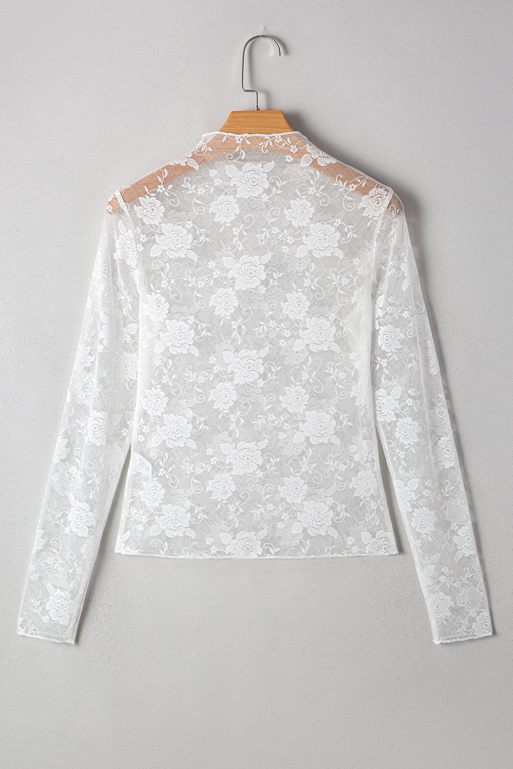 White lace blouse on a hanger against a gray background