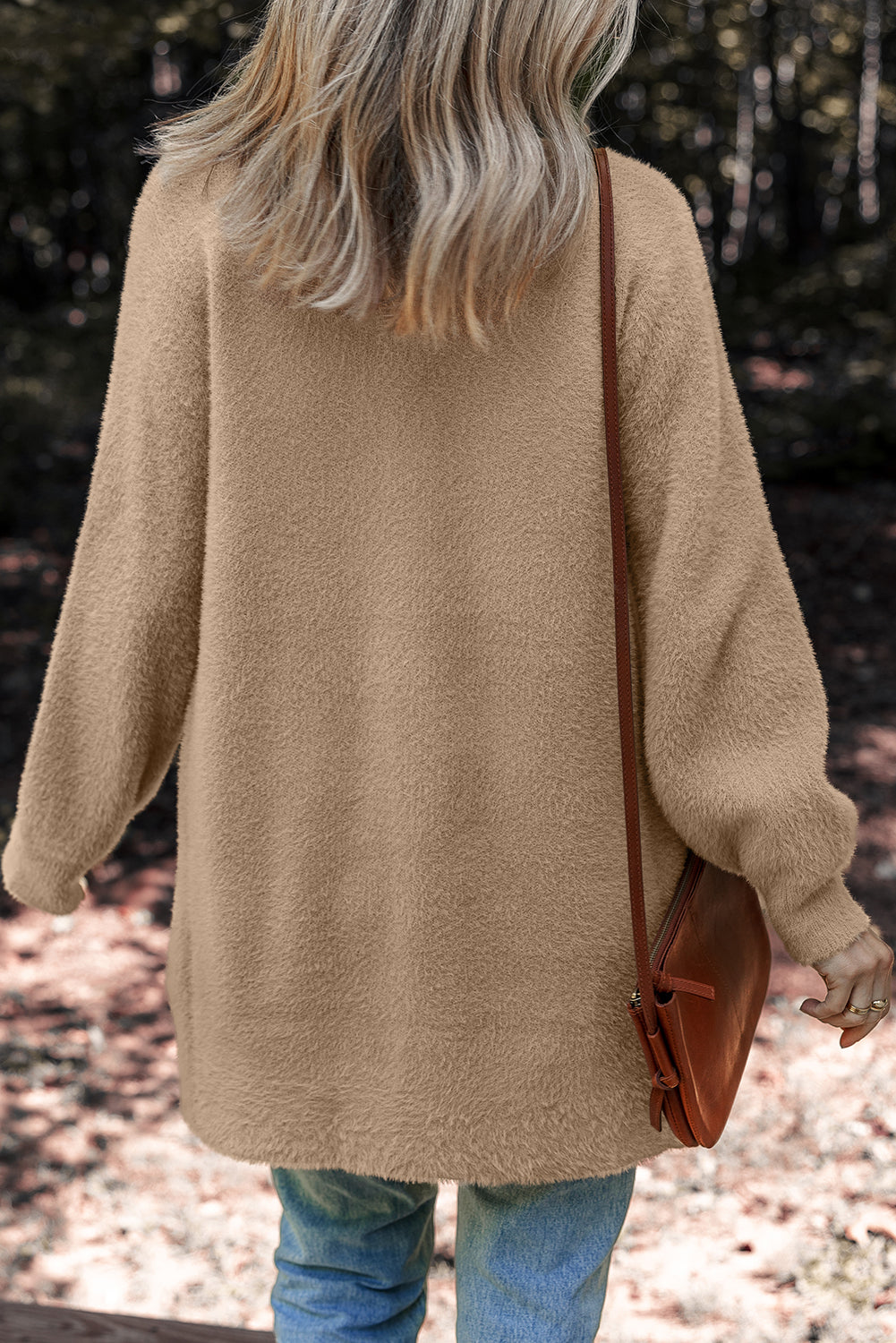 Person wearing a beige Fuzzy Buttoned Midi Cardigan and holding a brown bag. Back view